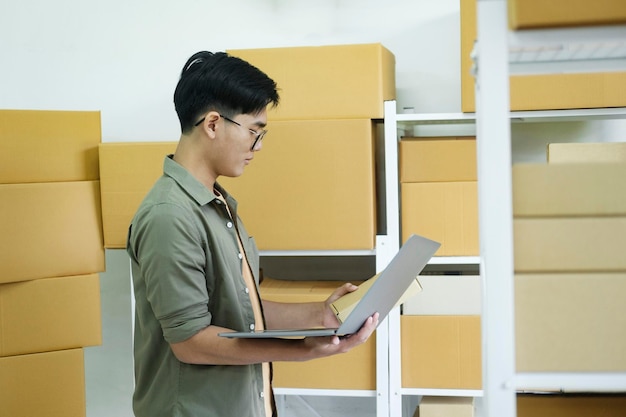 Young man checking parcel address using laptop