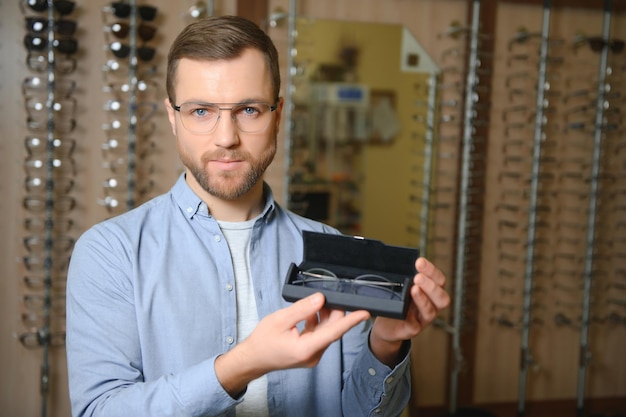 Young man choosing spectacles at optic shop