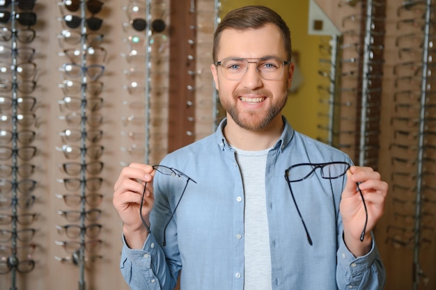 Молодой человек выбирает очки в оптическом магазине