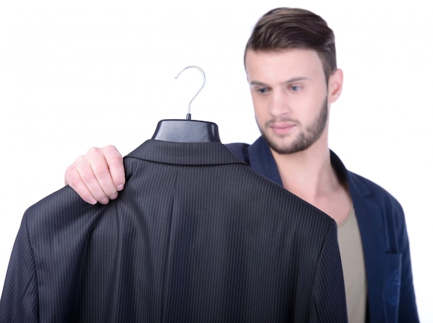 Young man choosing suit jacket in shopping.