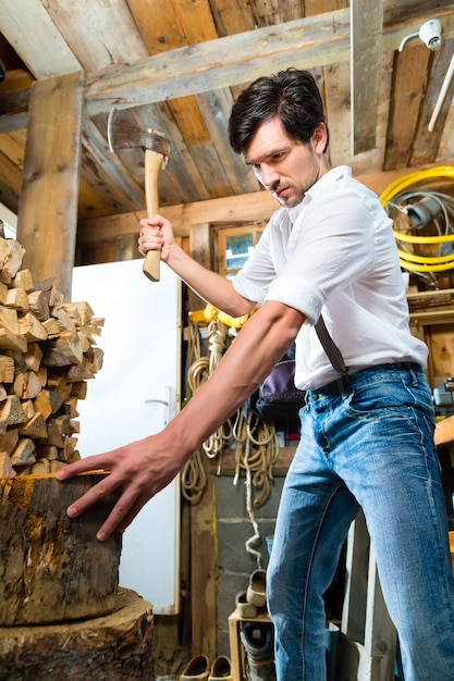 Young man chopping fire wood in mountain chalet