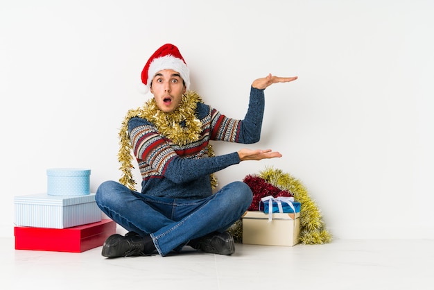 手のひらにコピースペースを保持しているクリスマスの日に若い男。