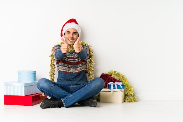 Young man on christmas day indicates with both fore fingers up showing a blank space.