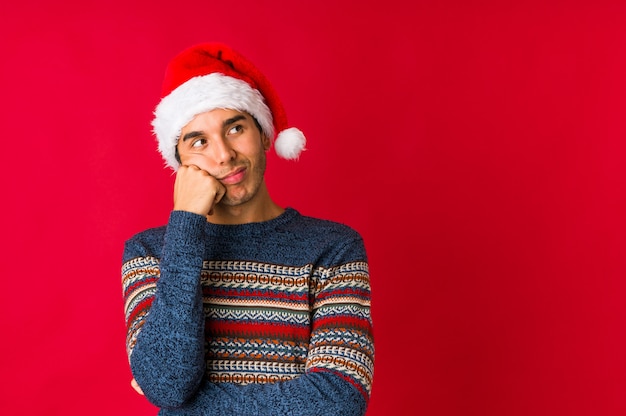 Young man on christmas day looking sideways with doubtful and skeptical expression.