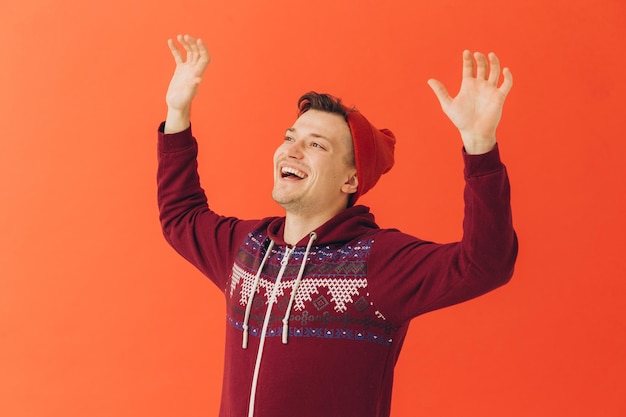 A young man in a Christmas kigurumi and a knitted hat on a colored background