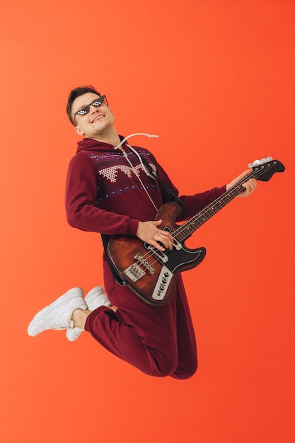 A young man in a Christmas kigurumi plays an electric guitar on a colored background