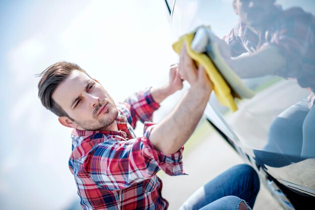 Young man cleaning his car outdoors