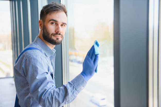 Young man cleaning window in office