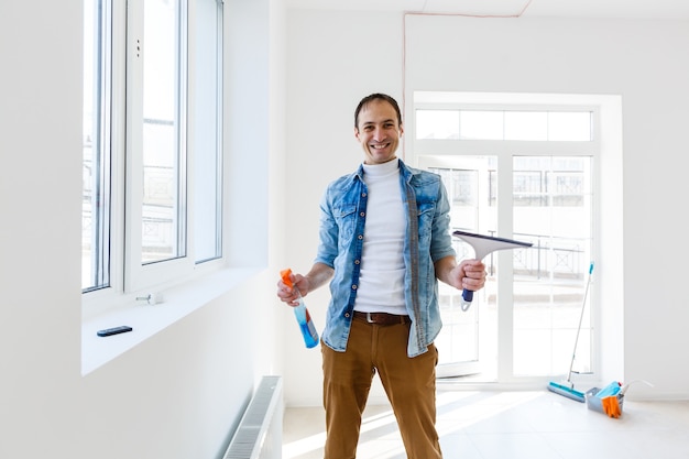 Young man cleaning window in office