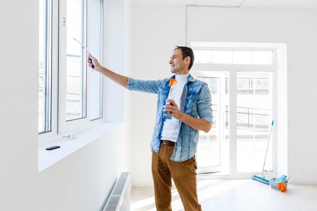 Young man cleaning window in office