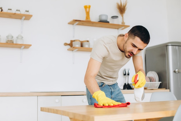 A young man cleans the kitchen at home wipes the table