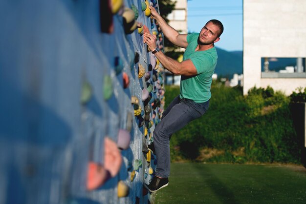 Photo young man climbing wall rock outdoors