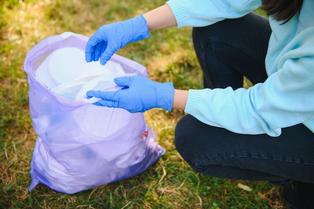 Young man collects garbage in a bag, volunteering