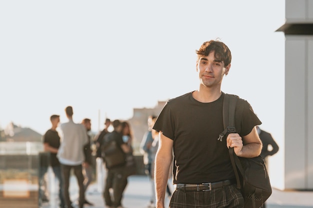 Young man college student walking with bag smiling happy. Student in high school campus looking serious worried about exams. Copy space. Business studies student during a master year in exchange