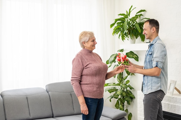 Young man come home to surprise his mother with bouquet of flowers.
