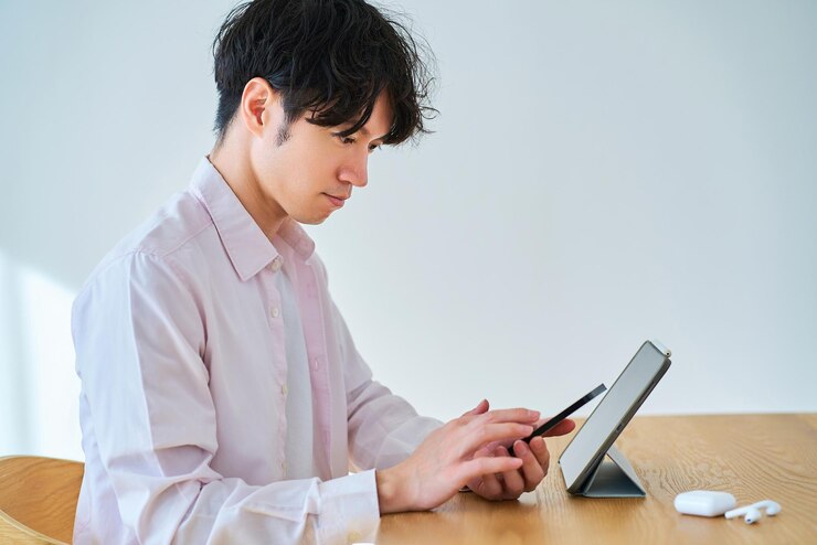 Photo タブレットpcとスマートフォンを比較する若者