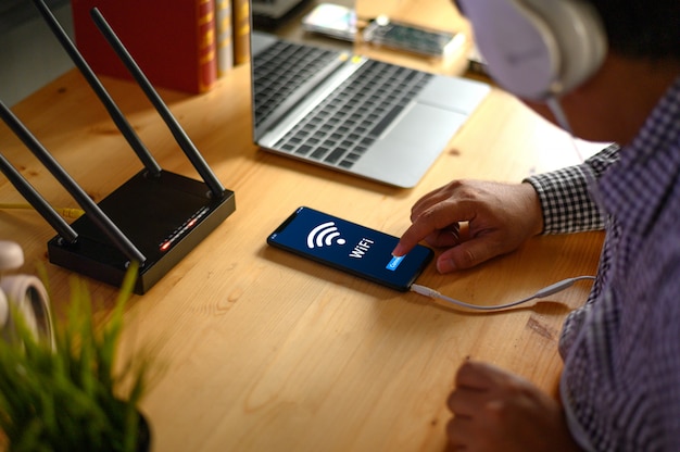 Foto giovane uomo che collega wifi router su smartphone per internet e social media