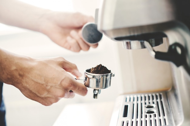 若い男が自宅で自動coffeemachineでコーヒーを調理します。