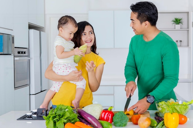 Young man cooking with his wife and daughter