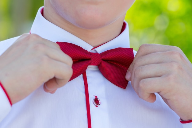 A young man corrects a red bow tie 