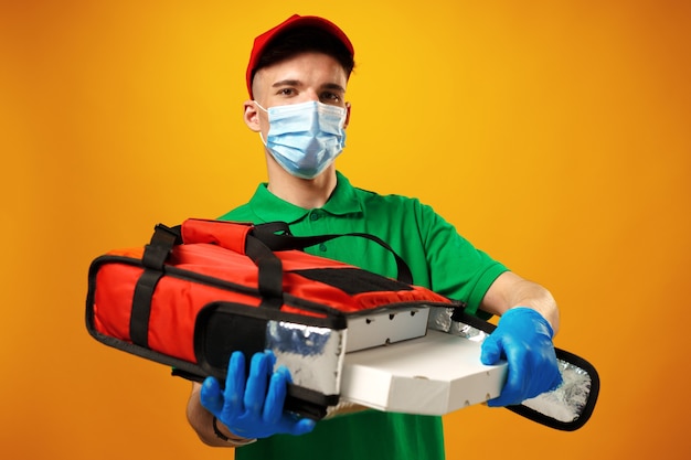 Young man courier in face mask with thermo bag