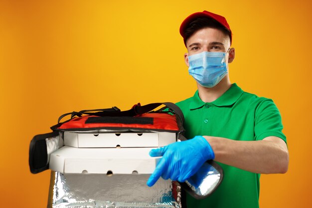 Young man courier in face mask with thermo bag