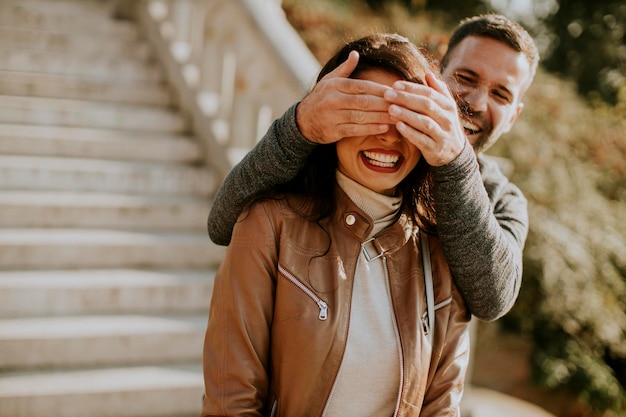 Young man covering the eyes of his girlfiend in the park