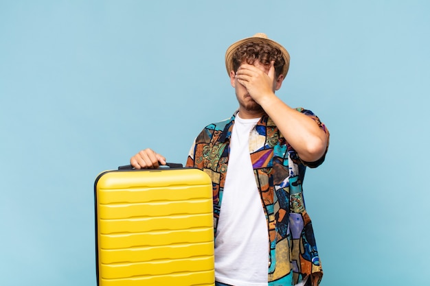 Young man covering face with hand and putting other hand up front to stop camera, refusing photos or pictures