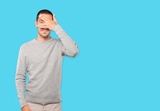 Photo young man covering his eyes with his hands