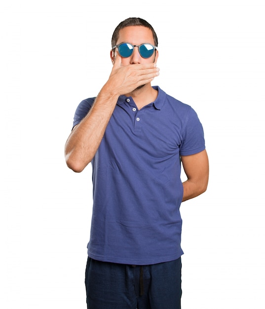 Young man covering his mouth on white background