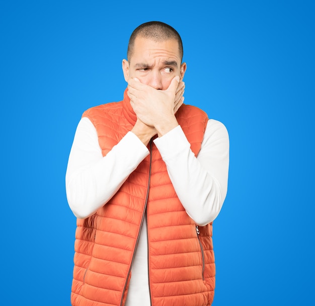 Young man covering his mouth with his hands