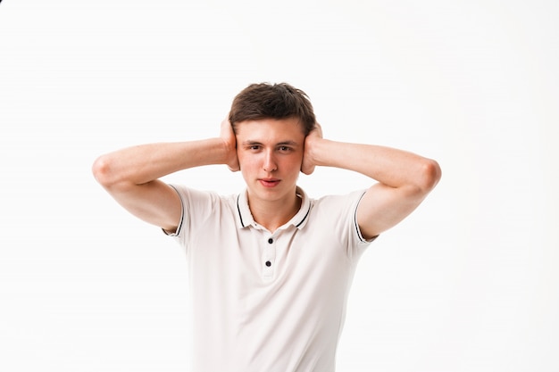 Young man covers his head and ears with his hands