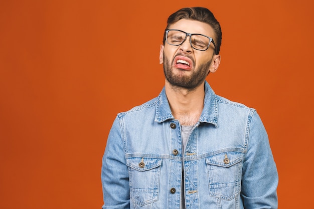 Young man crying isolated against orange background