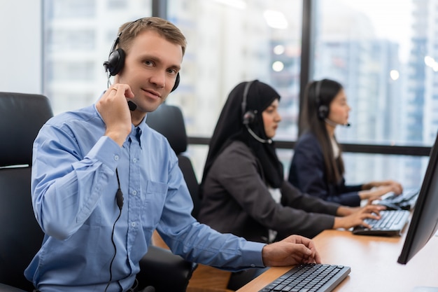 Young man customer service agent with headsets working on computer in a call centre