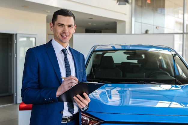 Young man dealer with clipboard in showroom