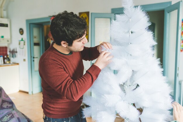 Young man decorating Christmas tree