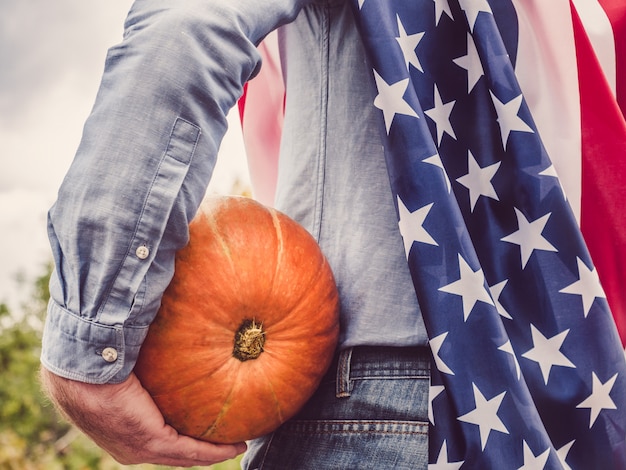 Young man in a denim shirt holding a ripe pumpkin