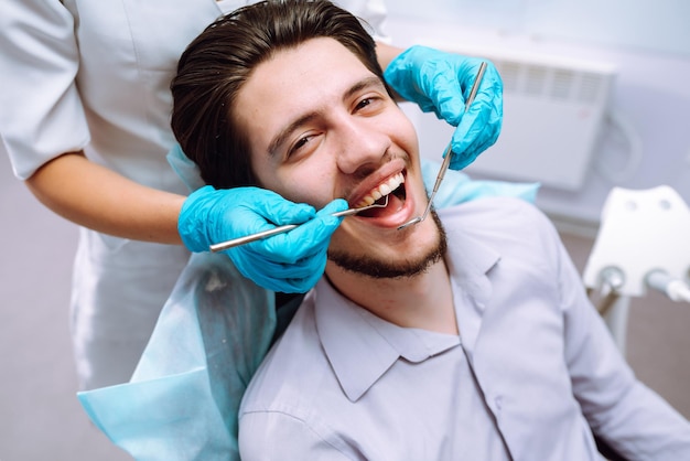 Young man at the dentist's chair during a dental procedure Overview of dental caries prevention