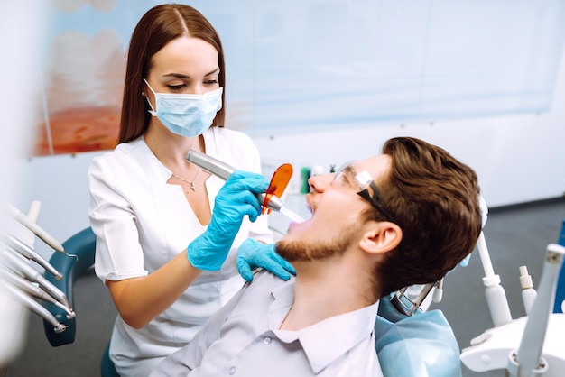 歯科の手術中に歯科医の椅子に座っている若い男 歯の腐敗の予防の概要