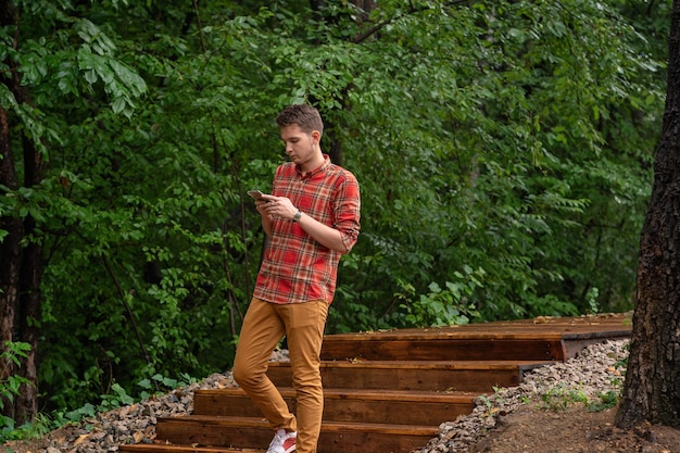 a young man descends the wooden steps in the park holding a phone