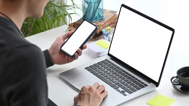 young man designer using smart phone and working with computer laptop at workplace.