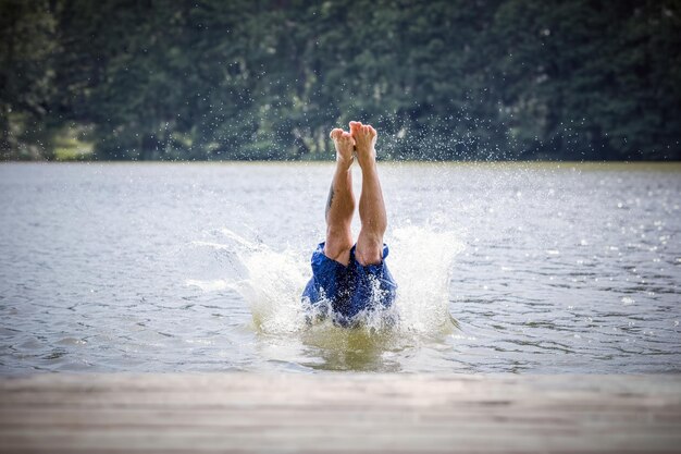 Photo young man diving into a lake careless and risky water jump summer vacation dangerous outdoor activity