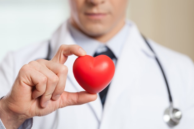 Young man doctor holding red heart