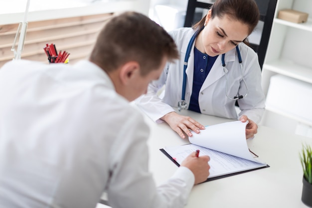 The young man at the doctor's office signs the documents. 