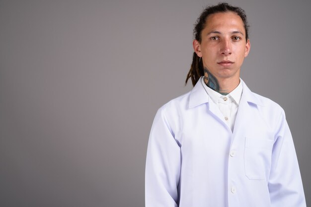 Young man doctor with dreadlocks against gray background