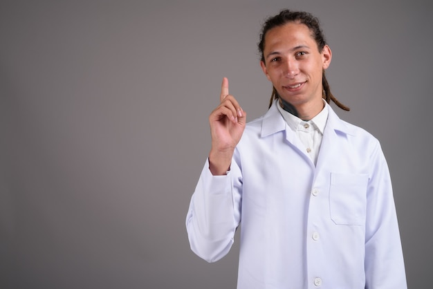 Young man doctor with dreadlocks against gray background