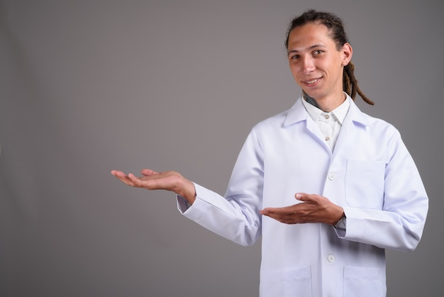 Young man doctor with dreadlocks against gray background