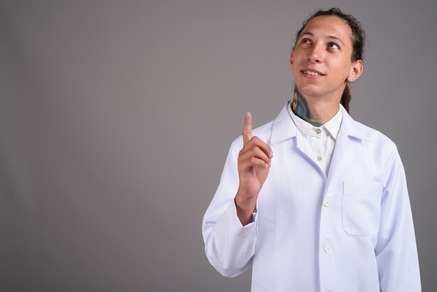 Young man doctor with dreadlocks against gray background