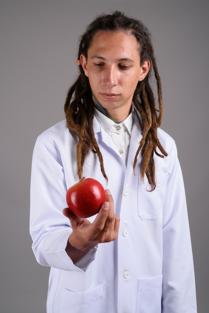 Young man doctor with dreadlocks against gray background