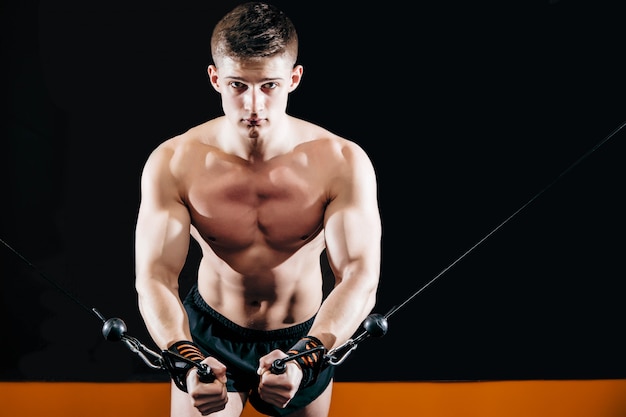 A young man does hand-cutting on the simulator in the gym